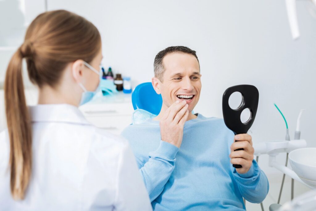 Pacjent ocenia swoje uzębienie w lustrze dentystycznym